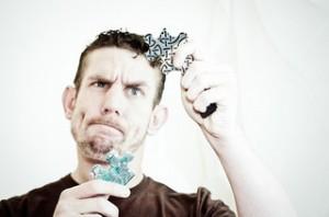 Confused man trying to put puzzle pieces together