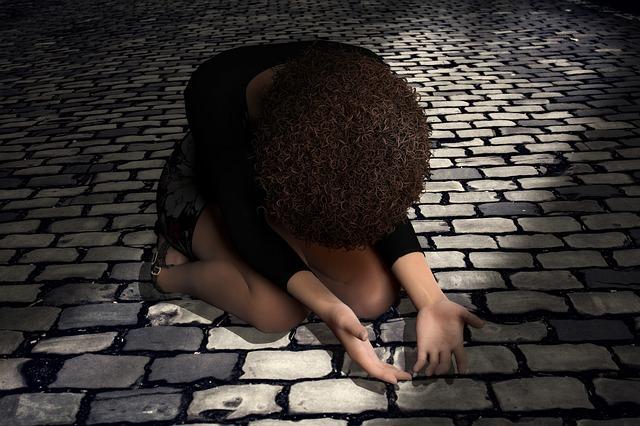 praying, kneeling woman on cobblestones