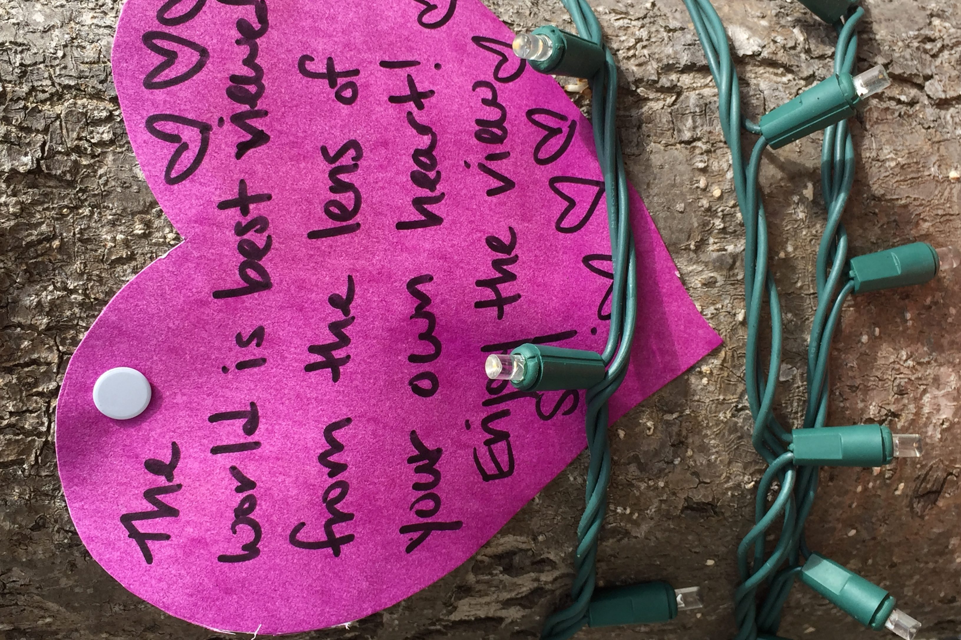 Paper heart tacked to tree, with motto
