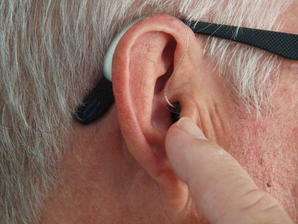 Man pointing to ear and hearing aid
