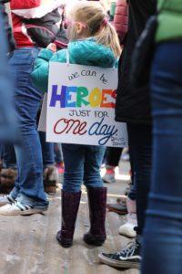Young girl wearing "We can be heroes" sign