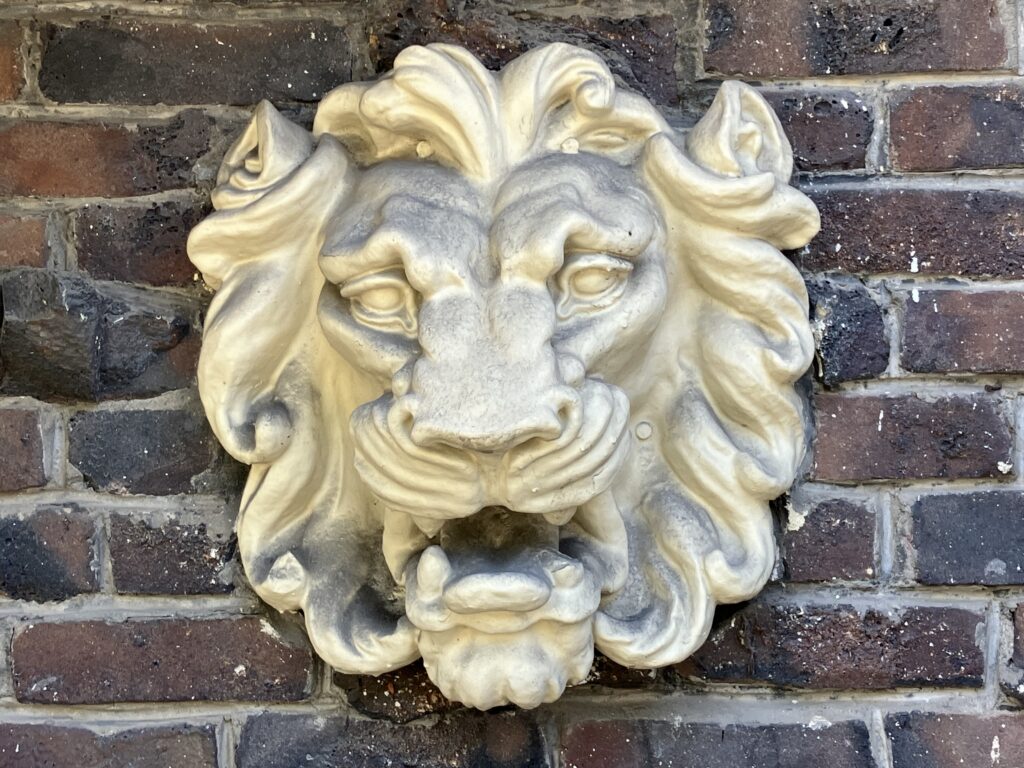 Plaster lion standing guard on brick wall in San Francisco