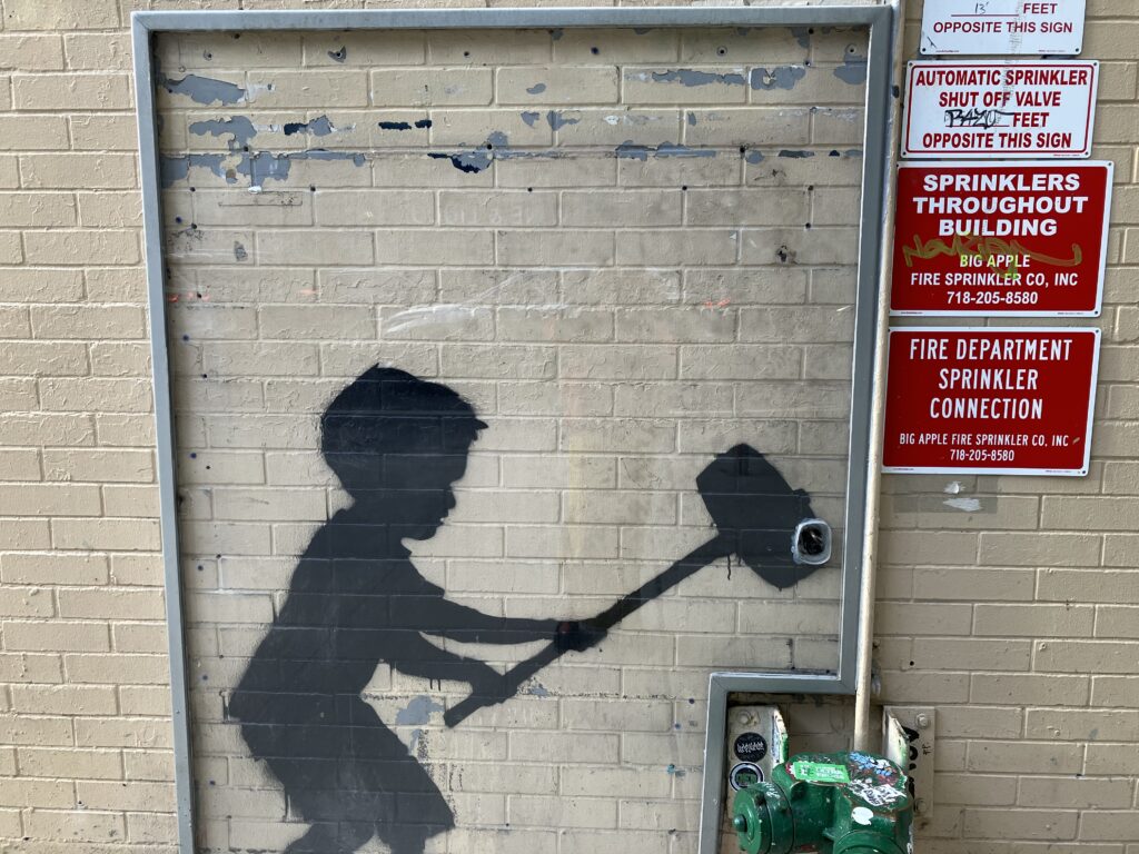 Banksy on a wall in Manhattan's upper west side. Behind a wall of protective glass.