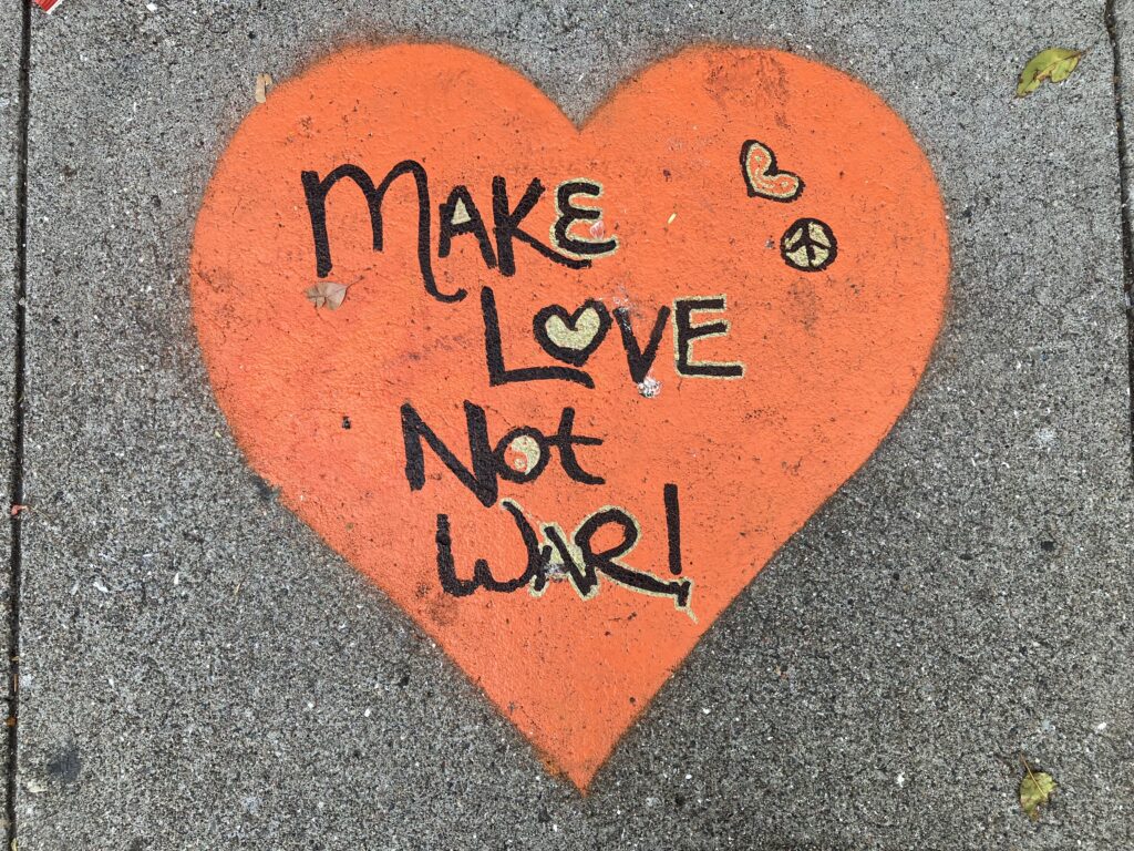 "Make Love Not War" chalked on a sidewalk