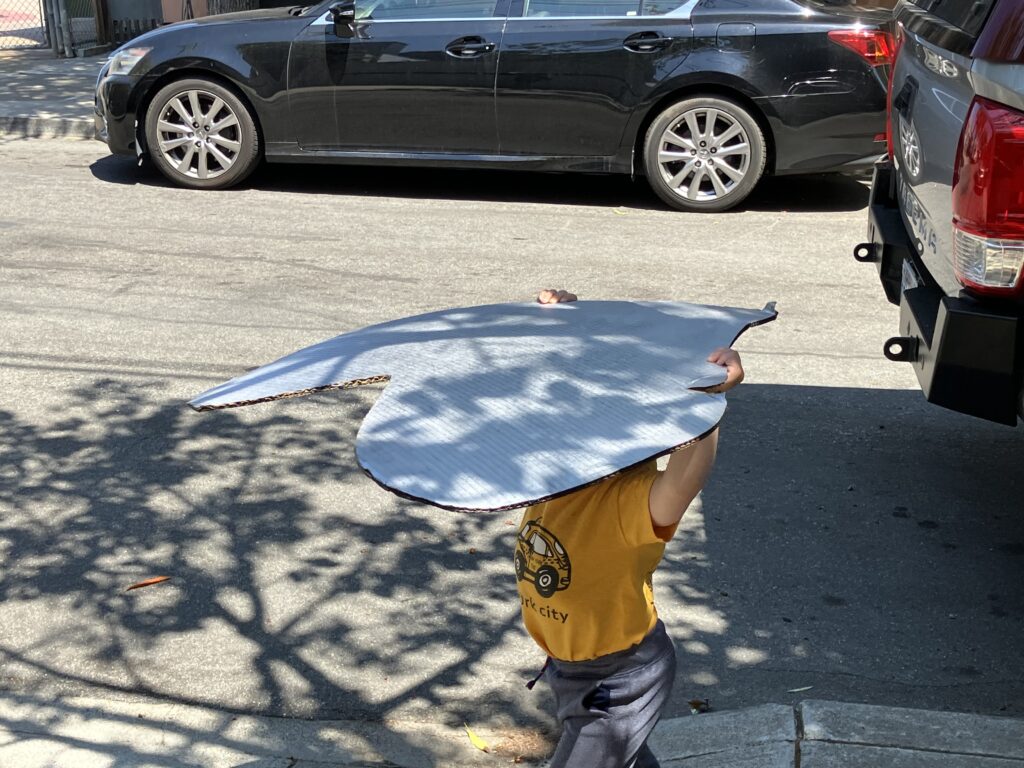 Little guy carrying a big cardboard heart down the street.