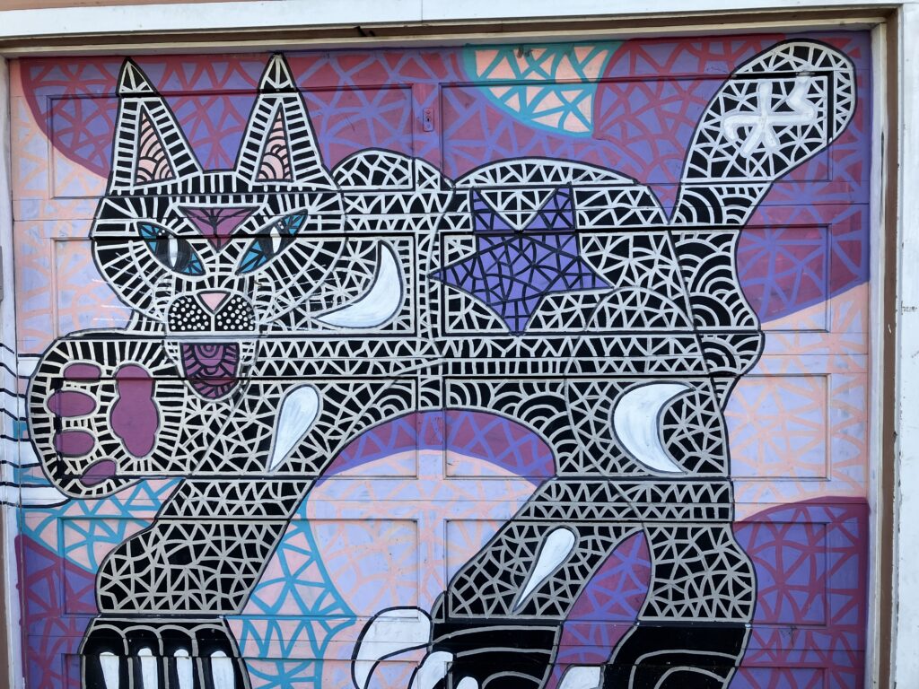 Lady cat mural spied on a garage door.