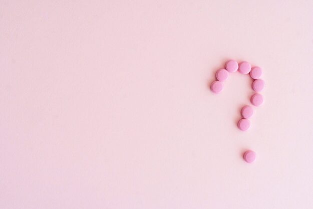 Small pink pills forming a question mark.