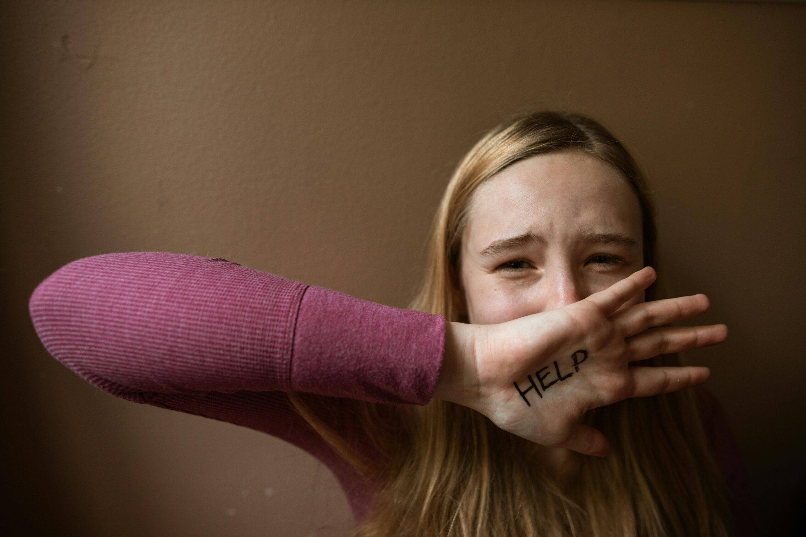 Woman showing "help" written on hand