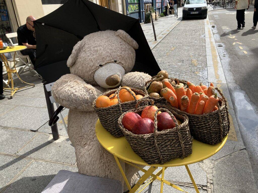 Giant stuffed bear vending vegetables on the street
